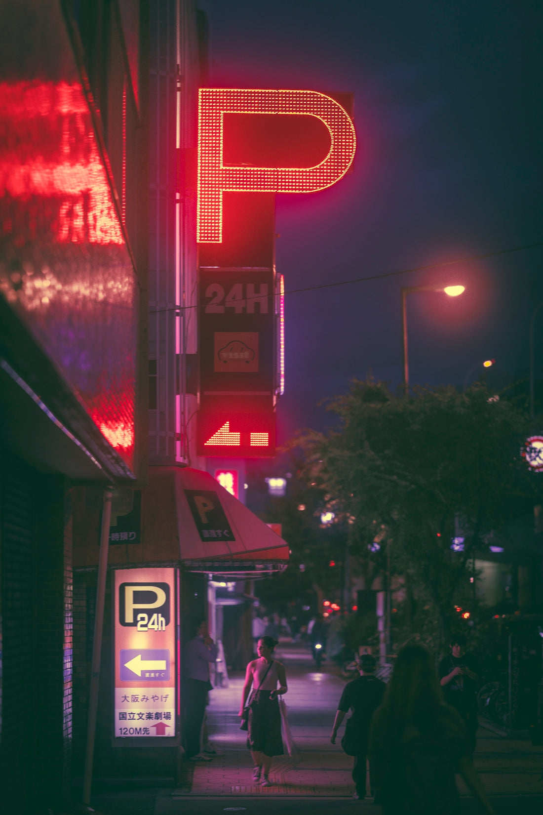a woman walking down a sidewalk next to a tall building