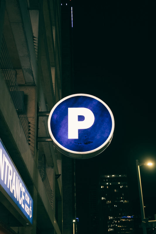 a blue parking sign hanging from the side of a building