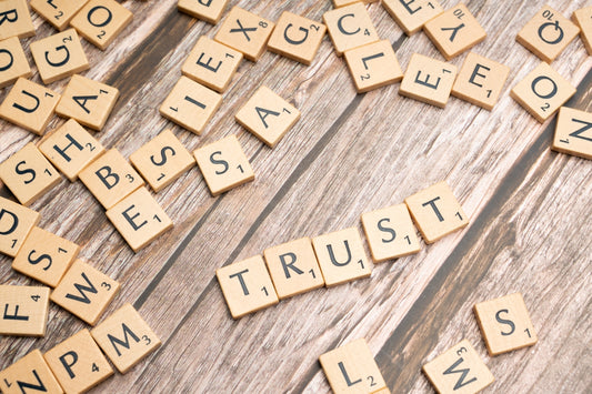 scrabble tiles spelling the word trust on a wooden surface