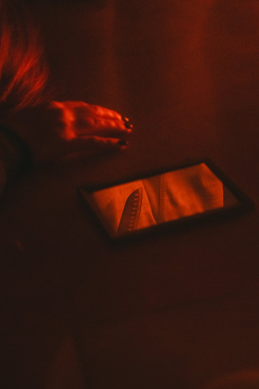 A hand and mirror reflect in red light.