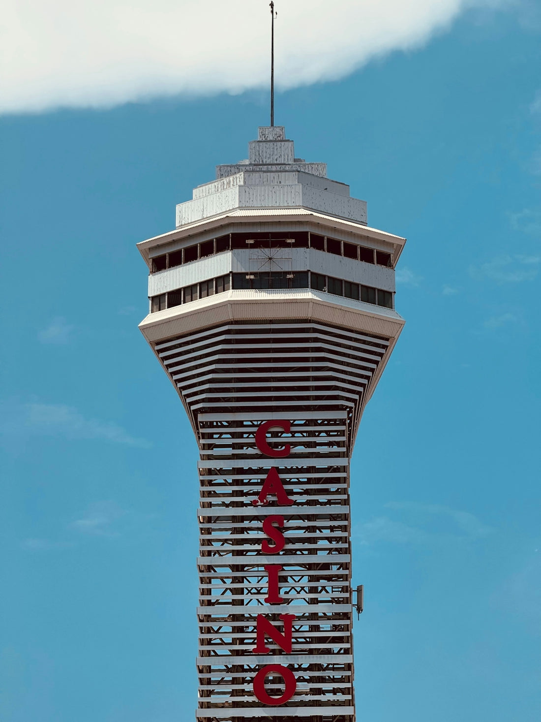 Tall tower with casino sign against blue sky.